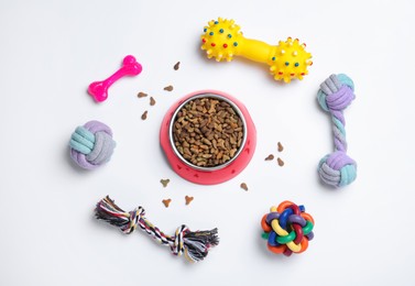 Different pet toys and feeding bowl on white background, top view