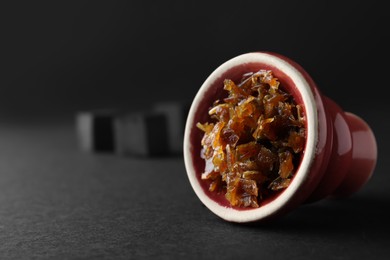 Red clay bowl of hookah with aromatic tobacco on black background, closeup. Space for text
