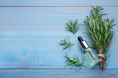 Bottle of rosemary essential oil and sprigs on light blue wooden table, flat lay. Space for text