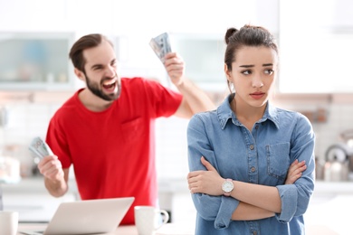 Photo of Young couple having argument about family budget in kitchen