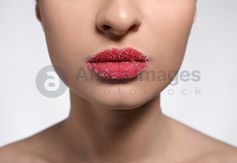 Young woman with lips covered in sugar on light background, closeup