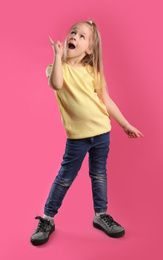 Full length portrait of emotional little girl on pink background