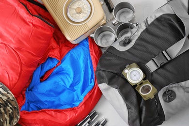 Flat lay composition with sleeping bag and camping equipment on grey background