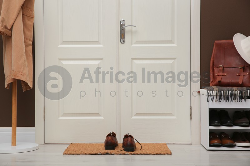 Shelving unit with shoes, coat rack and door mat in hall