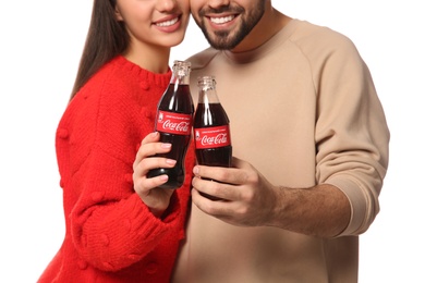 MYKOLAIV, UKRAINE - JANUARY 27, 2021: Young couple holding bottles of Coca-Cola against white background, closeup