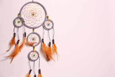 Beautiful handmade dream catcher on beige wall. Space for text