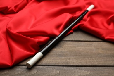 Beautiful black magic wand and red fabric on wooden table