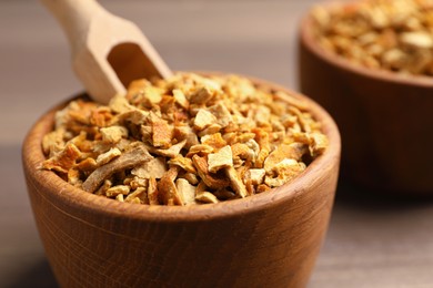 Photo of Bowls of dried orange zest seasoning on wooden table, closeup