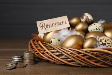 Card with word Retirement, many golden and quail eggs in nest on wooden table. Pension concept