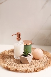 Soap dispenser, plant and burning candle on countertop in bathroom. Space for text