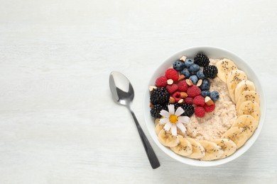 Tasty oatmeal porridge with berries, banana and chia seeds served on light wooden table, flat lay. Space for text