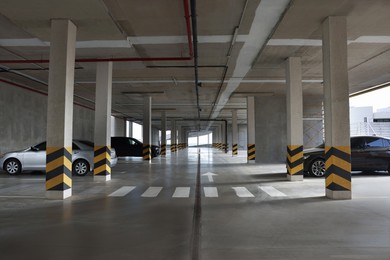 Modern cars in parking garage with pedestrian crossing