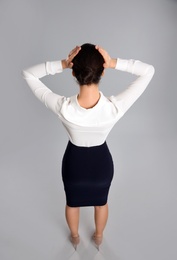 Photo of Young businesswoman in elegant suit on grey background, back view
