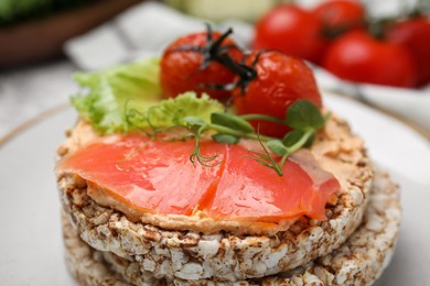 Crunchy buckwheat cakes with salmon, tomatoes and greens on plate, closeup