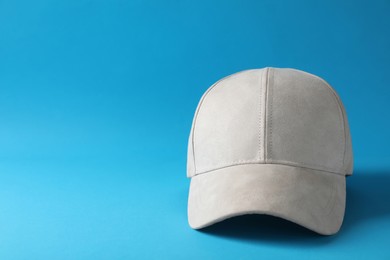 Stylish beige baseball cap on light blue background. Space for text