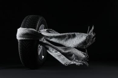Winter tire with grey scarf on black background