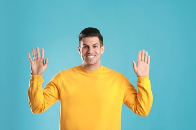 Photo of Cheerful man waving to say hello on turquoise  background