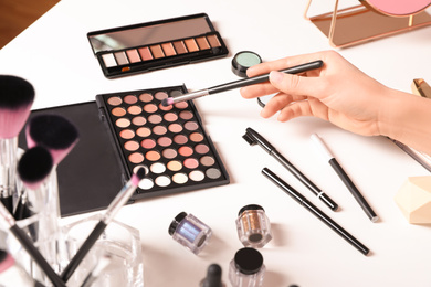 Beauty blogger with brush and eyeshadow palette at table, closeup