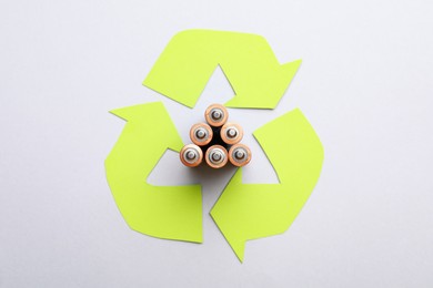 Photo of Used batteries and recycling symbol on white background, top view