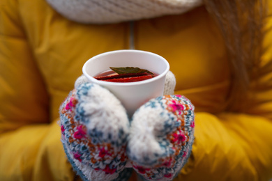 Woman in yellow jacket holding cup of mulled wine, closeup