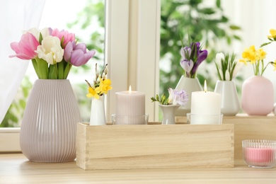 Photo of Beautiful spring flowers with burning candles on window sill