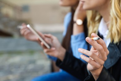 Photo of People smoking cigarettes at public place outdoors, closeup. Space for text