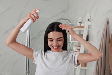 Woman applying dry shampoo onto her hair in bathroom
