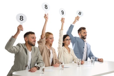 Panel of judges holding different score signs at table on white background