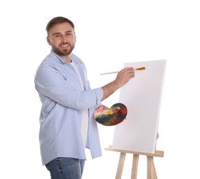 Man painting with brush on easel against white background. Young artist