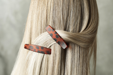 Young woman with beautiful hair clips on grey background, closeup