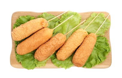 Delicious deep fried corn dogs with lettuce on white background, top view