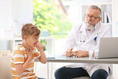 Coughing little boy visiting doctor at clinic