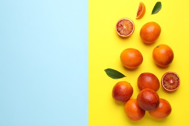 Many ripe sicilian oranges and leaves on color background, flat lay. Space for text