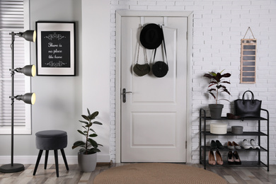 Hallway interior with stylish furniture, shoes and plants