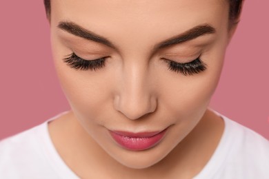 Beautiful young woman with long eyelashes on pink background, closeup