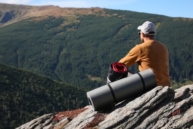 Tourist with sleeping bag and mat on mountain peak