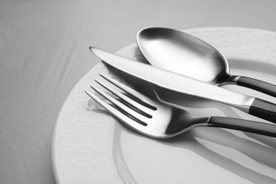 Plate with cutlery on grey table, closeup