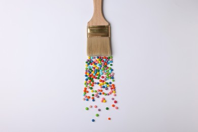 Brush painting with colorful sprinkles on light background, top view. Creative concept
