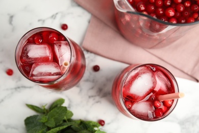 Tasty refreshing cranberry cocktails on white marble table, flat lay