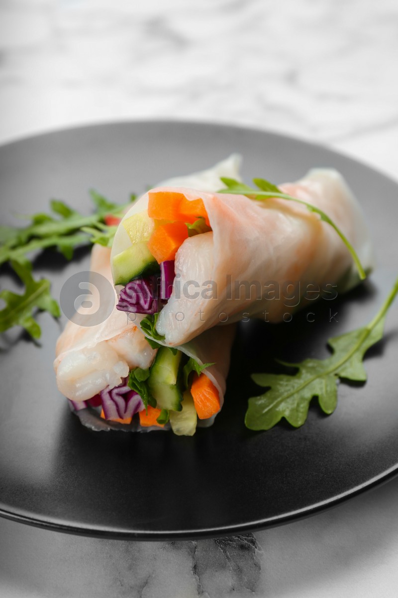 Delicious rolls wrapped in rice paper served on marble table, closeup