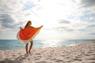 Beautiful woman with bright beach towel on sunlit seashore