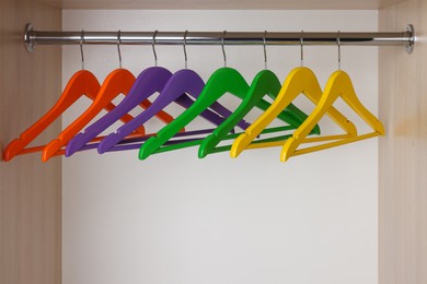 Set of bright clothes hangers on wardrobe rail