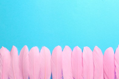 Beautiful pink feathers on light blue background, flat lay. Space for text