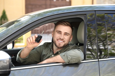 Image of Happy man with car key in his new auto 