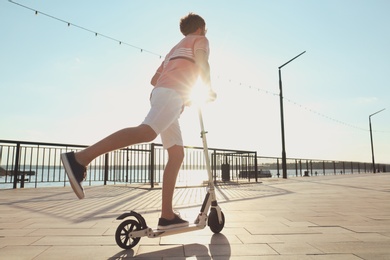 Man riding modern kick scooter along waterfront