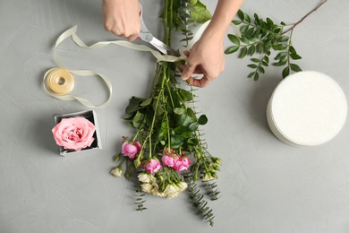 Female florist making beautiful bouquet at table, top view