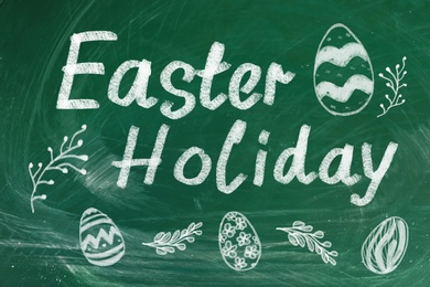 Text Easter Holiday and drawings on green chalkboard. School break 