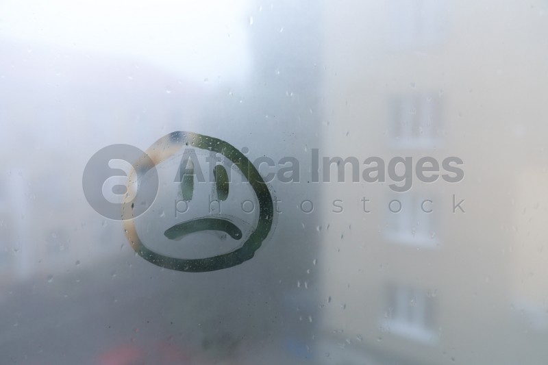 Sad face drawn on foggy window, space for text. Rainy weather