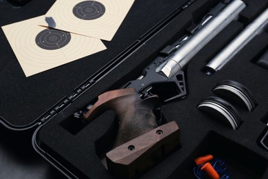 Case with sport pistol and accessories on black table, closeup. Professional gun