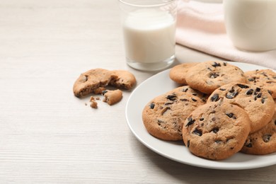 Plate with delicious chocolate chip cookies on white wooden table. Space for text
